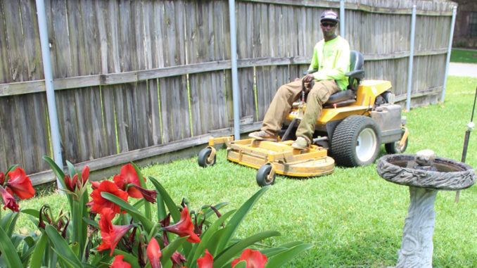 A worker with Quality Service Lawn and Landscape at work cutting grass.
